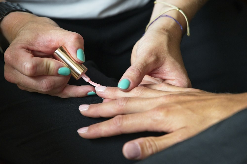 A nail tech painting a client’s nails